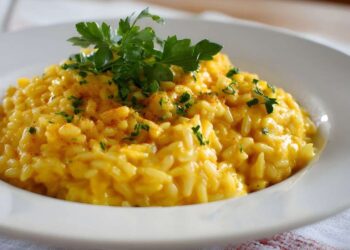 Un piatto di riso bianco fumante su un tavolo da cucina con un segnale di pericolo biologico rosso in primo piano