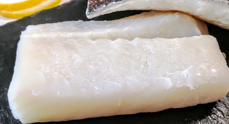 Affettate le cipolle finissime e fatele appassire in abbondante olio con le sarde dissalate finché queste ultime non si sciolgono. Aggiungete un goccio d’acqua per non bruciarle: questo creerà una base saporita in pochi minuti. Tagliate il baccalà in pezzi regolari, infarinateli leggermente e scuotete l’eccesso, quindi disponete il pesce sulle cipolle.