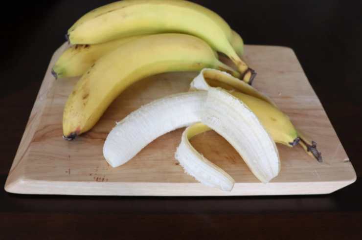 Lasciamo intiepidire il cioccolato per qualche minuto e, intanto, sbucciamo le banane e tagliamole a metà. Infilziamole su dei classici spiedini che fungeranno da manico e sostegno;