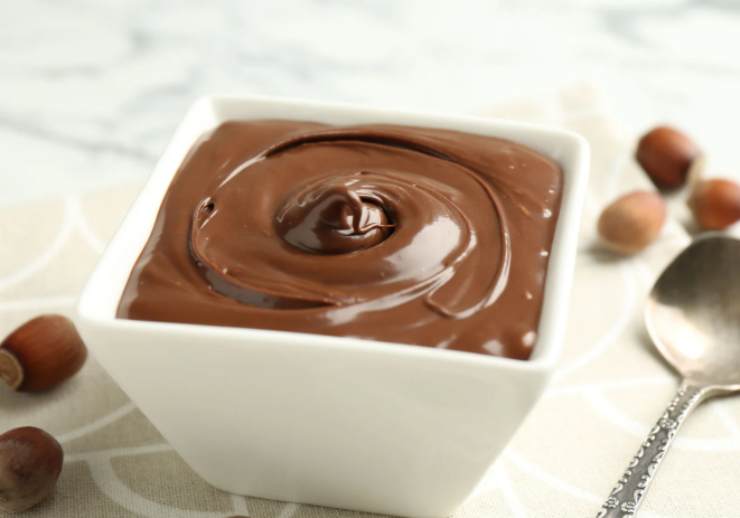 Uniamo al cioccolato bianco il cucchiaio di crema alla nocciola mentre è ancora caldo e mescoliamo, un po’ come facciamo col torrone. Andiamo invece a riversare metà del cioccolato al latte nello stampo livellando con cura. Lasciamo rassodare prima a temperatura e poi in frigo;