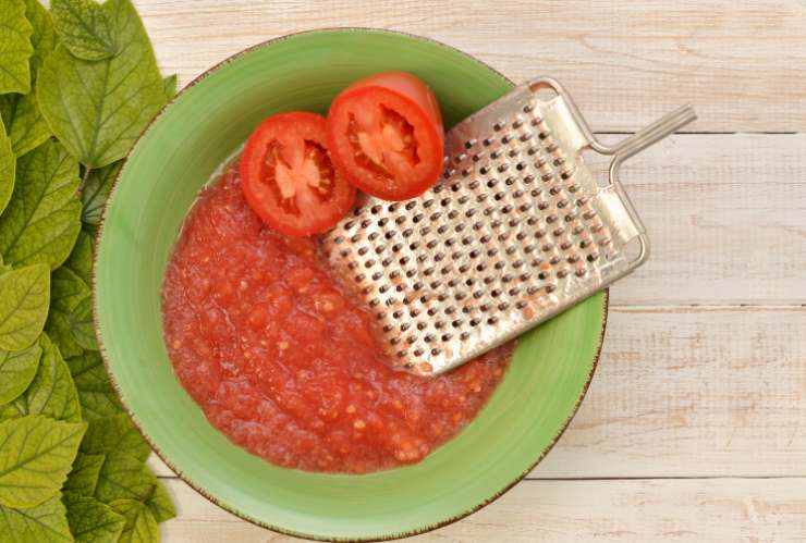 Intanto laviamo e asciughiamo i pomodorini e grattugiamoli finemente. Riversiamo la polpa in una ciotola e condiamo con olio d’oliva, sale e aromi a nostro gusto;