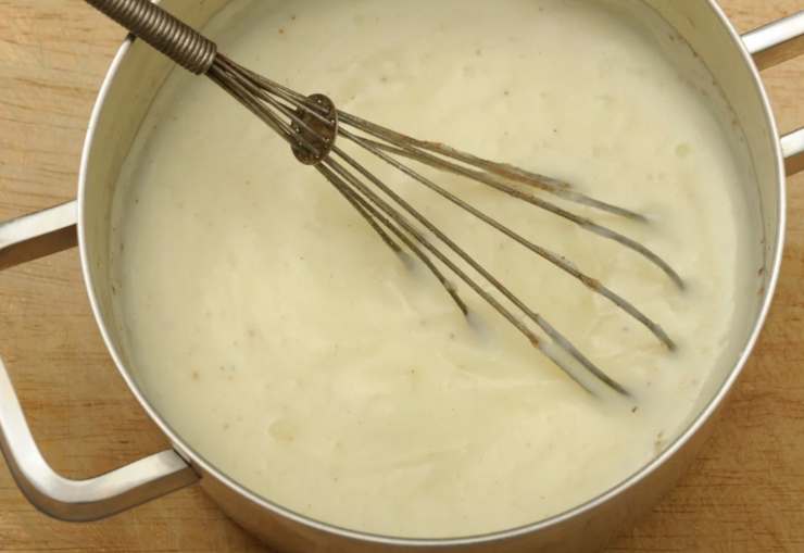 Scoliamo le patate e sgoccioliamole, intanto scaldiamo o prepariamo la besciamella. Prendiamo quindi una pirofila da forno e sul fondo versiamo un coppino di besciamella, spalmando;
