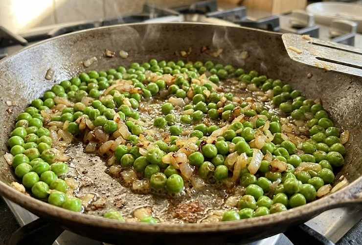 Scoliamo i piselli dal loro e riversiamoli in padella con la cipolla, mescoliamo e copriamo con un coperchio, lasciando cuocere il tempo necessario a intenerirli senza sfaldarli (se occorre possiamo aggiungere un goccio di acqua);