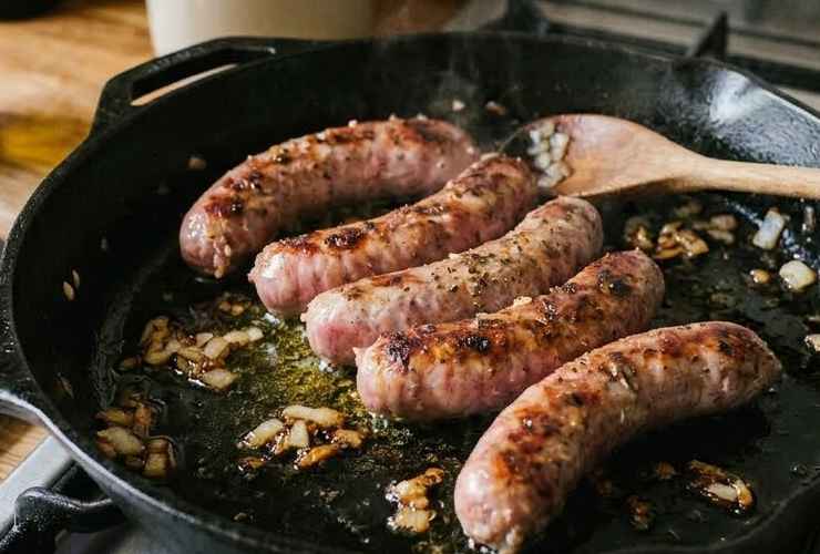 Intanto andiamo a rosolare in una padella capiente la cipolla tritata con olio d’oliva. Uniamo le salsicce e facciamo dorare, poi sfumiamo col vino bianco. Accorpiamo la passata di pomodoro, copriamo col coperchio e facciamo cuocere una mezz’ora a fiamma dolce;