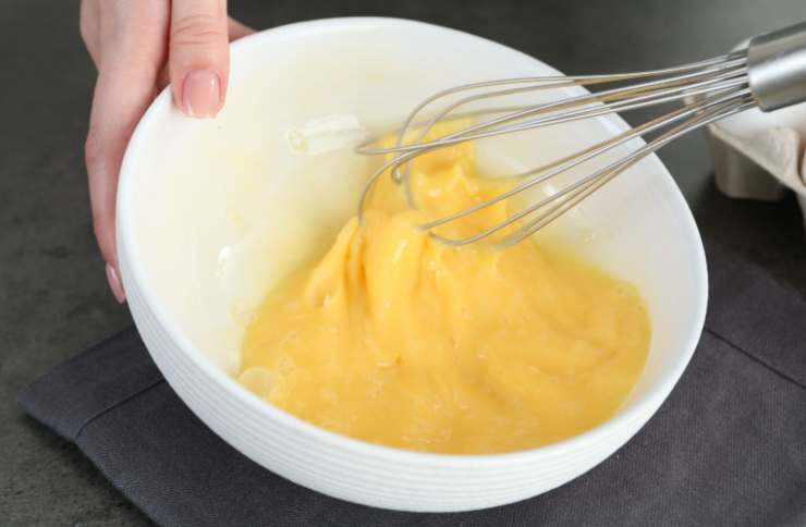 Rompiamo le uova in una ciotola, uniamo il resto dello zucchero e lavoriamo con un frullino fino a rendere spumose, poi accoriamo l’olio di semi e la ricotta, mescolando ancora;