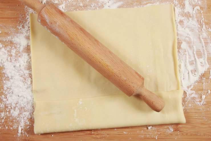 Stendiamo intanto il rotolo di sfoglia in uno stampo con bordi e modelliamo così da ottenere una base da riempire. In una ciotola a parte riversiamo la panna e uniamo le salsicce, quindi mescoliamo per amalgamare e controlliamo il sale;