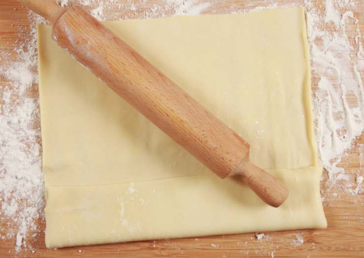 Stendiamo il rotolo di sfoglia di una superficie piana e tagliamo in quattro fette nel senso della lunghezza. Dividiamo a loro volta le fette a metà ottenendo, così, 8 strisce;