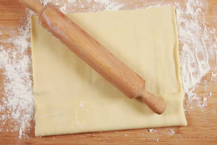 Stendiamo il rotolo di sfoglia e tagliamo dei cerchi della larghezza del bordo di un bicchiere. Andiamo a imburrare con cura una teglia da muffin o cupcake e adagiamo i cerchi all’interno, modellando anche i bordi;