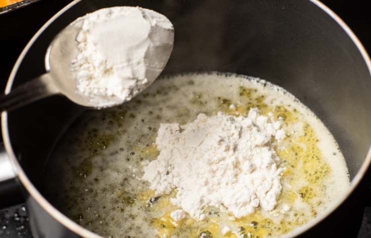 In un tegame andiamo a riversare il burro e sciogliamo a fiamma dolce, quindi uniamo la farina e mescoliamo, come facciamo quando prepariamo la besciamella classica. Intanto scaldiamo il latte e, una volta caldo, uniamo al burro e alla farina, mescolando finché non otteniamo la densità desiderata;