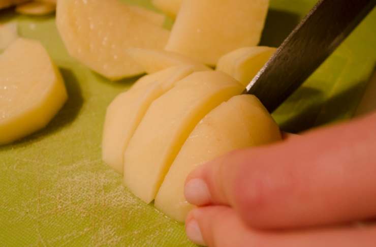 Iniziamo lavando le patate e sbucciandole, quindi andiamo a tagliarle a fettine di medio spessore (circa un cm) e sbollentiamole in acqua salata per 10 minuti, il tempo di intenerirle appena;