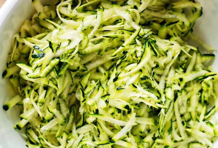 Per cominciare laviamo le zucchine, asciughiamole e spuntiamole, poi grattugiamole e strizziamole. Intanto sbricioliamo il pane e sistemiamo in una ciotola con un goccio di latte;