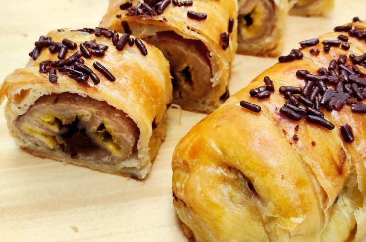 Avvolgiamo le strisce in modo che le banane e la crema siano all’interno. Adagiamo in una teglia foderata di carta da forno e spennelliamo con burro fuso misto a latte. Cuociamo a 180 gradi per un quarto d’ora circa, finché la sfoglia sarà dorata. Spolveriamo con lo zucchero a velo et voilà.