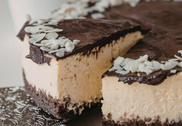 Riprendiamo lo stampo e andiamo a riversare sulla crema ormai soda il cioccolato fondente fuso e stendiamo con una spatola. Spolveriamo la farina di cocco e riportiamo in frigo un’ultima volta lasciando assestare per mezz’ora. Riprendiamo la torta, togliamo la cerniera e tagliamo a fette.