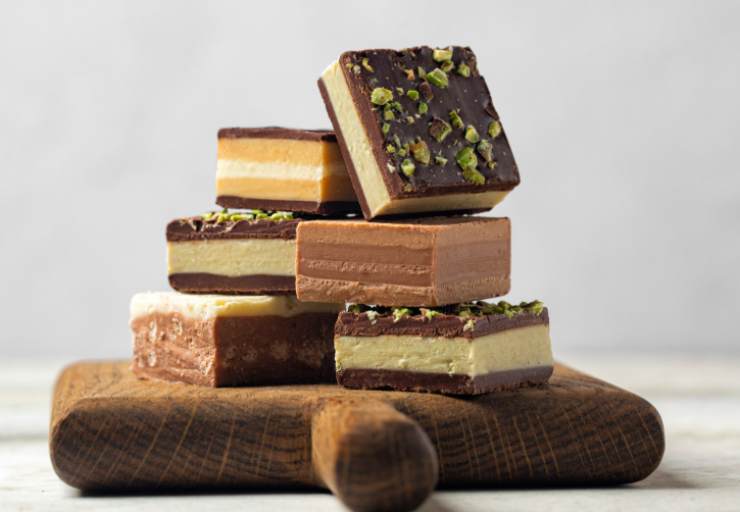 Quando il primo strato è sodo ricopriamo con il cioccolato bianco mescolato alla crema di nocciole. Di nuovo lasciamo rassodare e, per ultimo, ricopriamo ancora con il cioccolato al latte. Lasciamo in frigo, stavolta, una mezz’ora. Estraiamo dallo stampo aiutandoci con la carta da forno e tagliamo a quadretti: fenomenali.