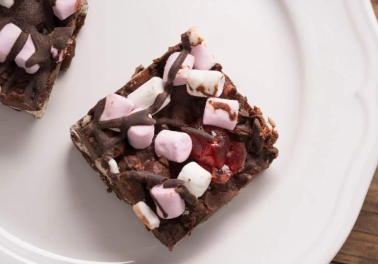 Riversiamo il composto ottenuto in una teglia da forno foderata dai bordi alti e lasciamo raffreddare prima a temperatura. Mettiamo quindi in frigo e lasciamo rassodare per una mezz’ora, anche un’ora. Non resta che tagliare a quadrotti e assaggiare: irresistibili!