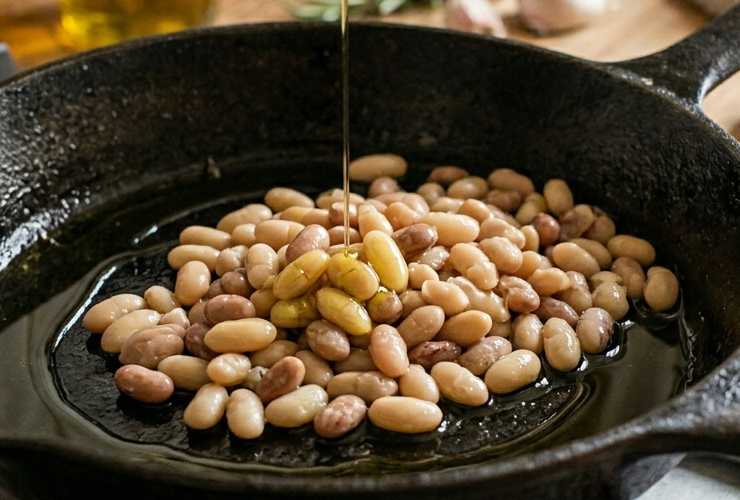A questo punto versiamo in padella anche i fagioli precotti e sgocciolati e dopo averli rosolati riversiamo sopra un bicchiere di acqua. Copriamo col coperchio e lasciamo cuocere fino ad ammorbidire (circa un quarto d’ora), quindi uniamo le salsicce dorate e saltiamo per un paio di minuti. Intanto la pentola con l’acqua per la pasta avrà raggiungo il bollore, saliamo e caliamo;