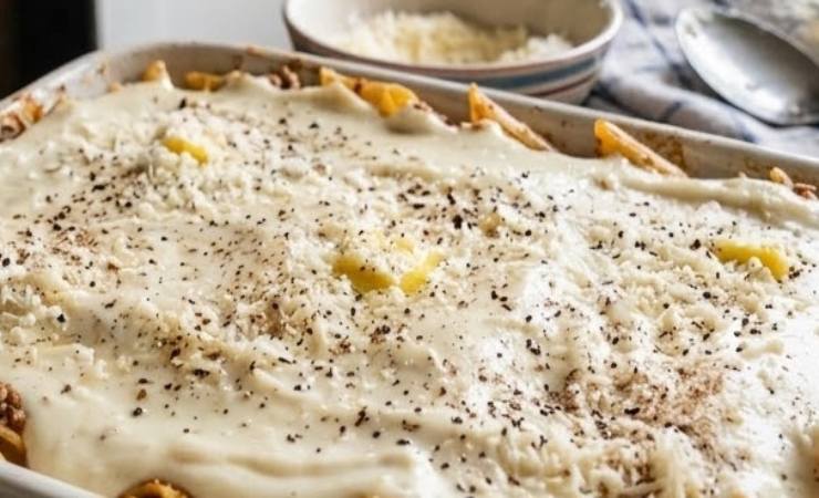 Condiamo la pasta con un paio di coppini di besciamella e poi con il misto di ingredienti. Mescoliamo e spolveriamo col parmigiano. Sul fondo di una teglia da forno versiamo un coppino di besciamella e poi riversiamo la pasta. Ricopriamo con altra besciamella;