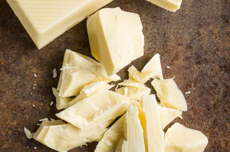 Per prima cosa sminuzziamo il cioccolato bianco. In una ciotola andiamo a versare la farina di mandorle e lo zucchero a velo, poi setacciamo l’amido di mais e il lievito e infine uniamo la vanillina. Mescoliamo per amalgamare tutte le polveri;