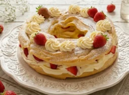 Grande zeppolone di pasta choux farcito con crema chantilly diplomatica e fragole fresche su un vassoio di ceramica decorata in una cucina luminosa stile shabby chic.