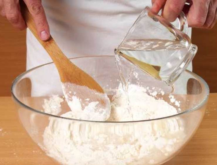 In una ciotola, sciogliete il lievito ed il miele nell’acqua: aggiungete tutta la farina e mescolate grossolanamente con un cucchiaio finché non ci sarà più farina. Coprite e lasciate riposare 20 minuti. Aggiungete ora il sale e l’olio: iniziate ad impastare con le mani portando i bordi dell’impasto verso il centro. L’impasto dovrà risultare appiccicoso: non aggiungete farina!