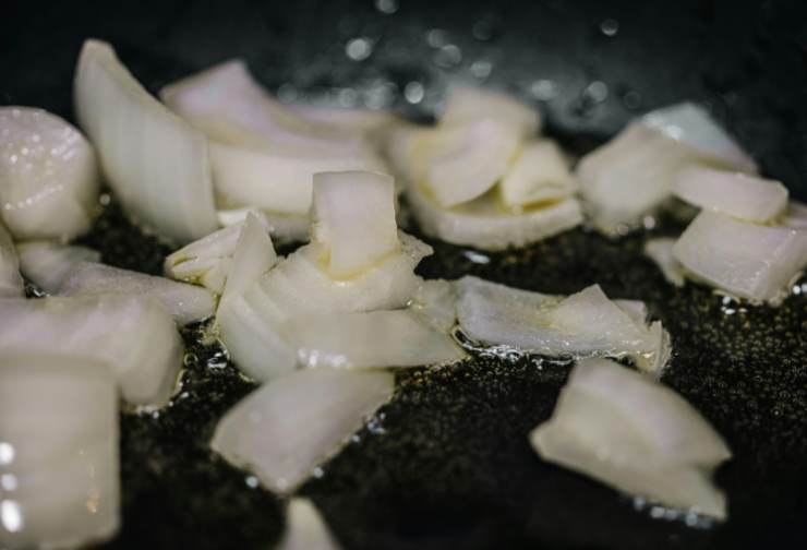 Scoliamo le patate, sgoccioliamole con cura e lasciamole intiepidire. Intanto tritiamo la cipolla. Versiamo un giro d’oliva in una padella capiente e facciamo appassire la cipolla;