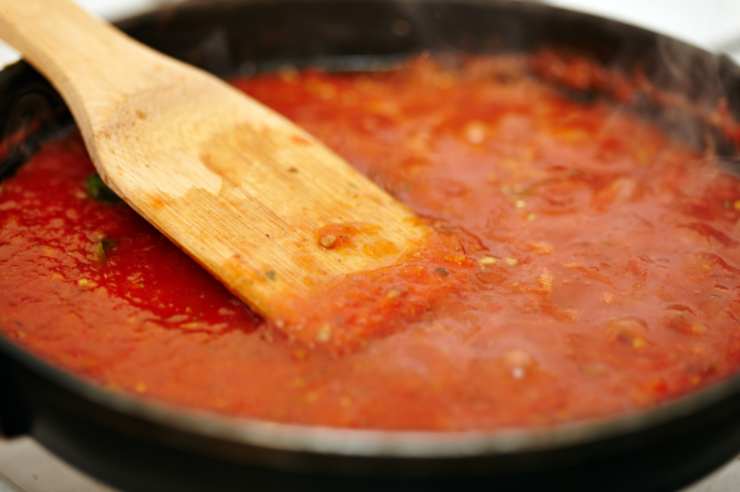 Quando l’aglio inizierà a colorirsi uniamo il peperoncino sbriciolato, lasceremo dorare e uniremo i pelati. Copriremo con un coperchio e lasceremo cuocere una decina di minuti. Potremo, intanto, salare l’acqua della pasta e calare le nostre penne;