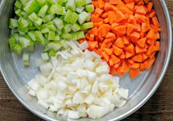 Aggiungiamo il misto di carote, sedano e cipolle tritati, mescoliamo con cura e lasciamo appassire le verdure insieme alla carne per qualche minuto. Sfumiamo ora con il vino rosso;