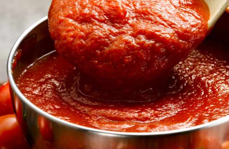 Mescoliamo per un paio di minuti, finché i chicchi non diventano lucidi. Versiamo la passata di pomodoro in padella e mescoliamo, quindi copriamo con un coperchio e lasciamo andare la cottura a fiamma bassa. All’occorrenza aggiungiamo acqua, fino a quando il riso non sarà quasi del tutto tenero: a questo punto togliamo il coperchio e lasciamo assorbire il liquido in eccesso;