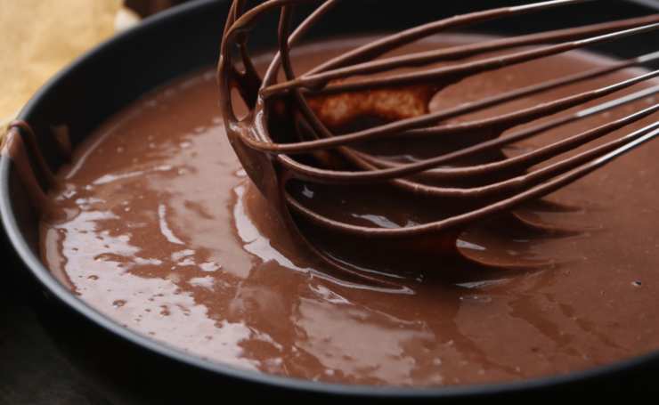 Accorpiamo due uova e mescoliamo, poi versiamo nella crema metà del cioccolato e di nuovo due uova. Aggiungiamo il cioccolato rimasto e mescoliamo ancora fino a ottenere un composto omogeneo;