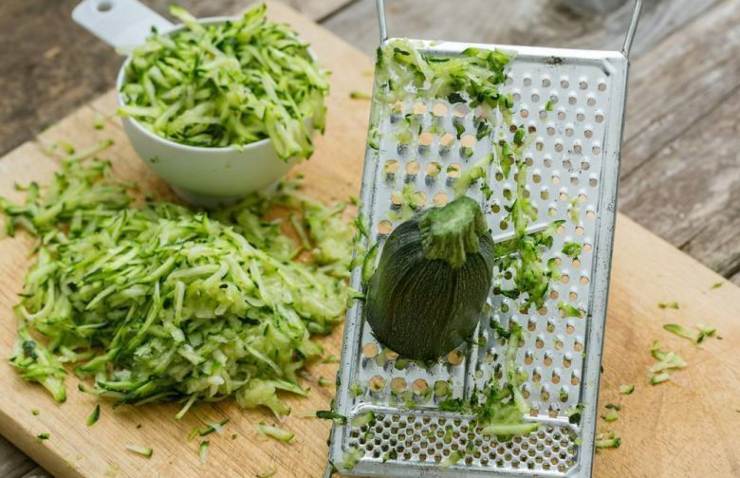 Grattugiate le zucchine usando i fori larghi di una grattugia a mano, quindi mettetele in un colino, salatele leggermente e lasciate riposare 10 minuti. Fatto ciò prendete poche zucchine alla volta tra le mani e strizzatele con forza (o usate un canovaccio pulito) finché avranno perso tutto il liquido. Devono risultare quasi asciutte.