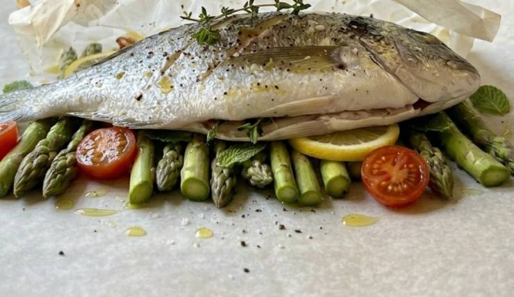 Condite con un filo d’olio extra vergine d’oliva, un goccio di vino bianco ed il succo di limone. Aggiungete poi il timo ed il prezzemolo tritati finemente e chiudete i lembi della carta forno verso l’alto. Sigillate bene le estremità (potete usare anche dello spago da cucina o semplicemente ripiegare i bordi) in modo che diventi un pacchetto ermetico.