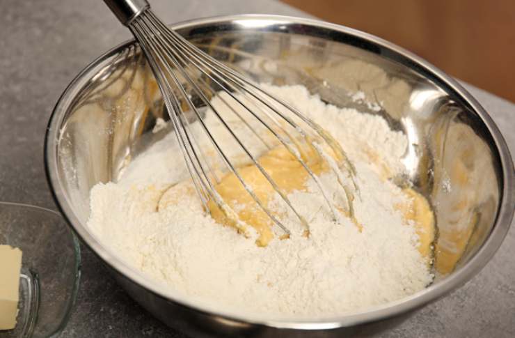 Prendiamo una ciotola e versiamo all’interno la farina, il lievito e l’amido di mais. Mescoliamo e uniamo lo zucchero e la vanillina, quindi mescoliamo ancora. Andiamo ora a unire il burro a pezzi;