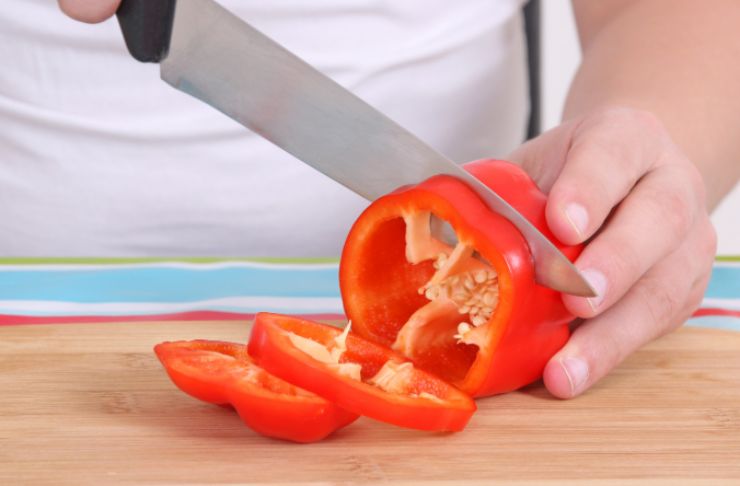 Laviamo i peperoni e tagliamoli a fiammiferi o pezzetti dopo aver eliminato semi e fili. Rosoliamo il pizzico di aglio in polvere in una padella antiaderente con un filo d’olio d’oliva e uniamo i peperoni;