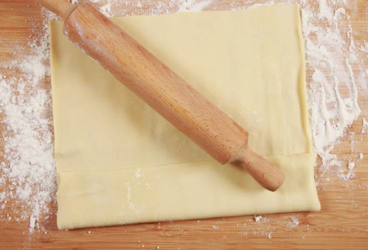 Stendiamo il primo rotolo di sfoglia in una teglia da forno dai bordi alti e foderato. Modelliamo anche i bordi;