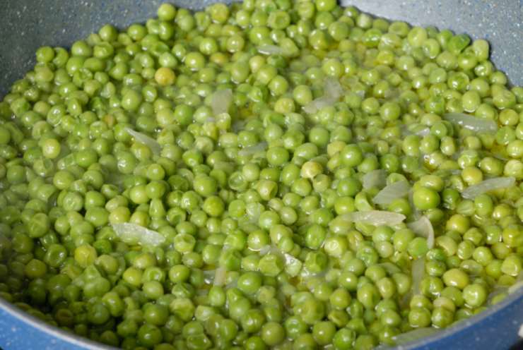 Riversiamo i piselli in un tegame con un filo d’olio d’oliva e mezza cipolla tritata. Lasciamo rosolare e copriamo con un coperchio, cuocendo a fiamma dolce fino a intenerirli (uniamo un goccio d’acqua se serve). Una volta cotti riversiamoli in un frullatore e riduciamoli in crema;