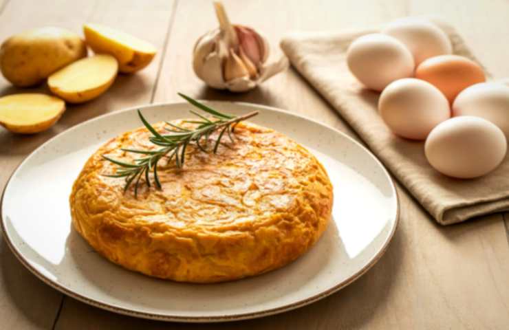 Scaldiamo una padella antiaderente con un filo d’olio d’oliva e una volta calda riversiamo il composto. Copriamo col coperchio e cuociamo a fiamma dolce fino a dorare un lato, quindi capovolgiamo e lasciamo dorare anche l’altro. Una volta cotta sistemiamo la frittata in un vassoio e tagliamo a fette.