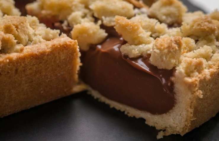 Riprendiamo la torta e spolveriamo sopra le briciole di biscotti rimaste ricoprendo completamente la crema. Di nuovo mettiamo in frigo per un quarto d’ora, poi delicatamente togliamo la cerniera e spostiamo in un vassoio usando la carta da forno sottostante. Non resta che tagliare e servire.