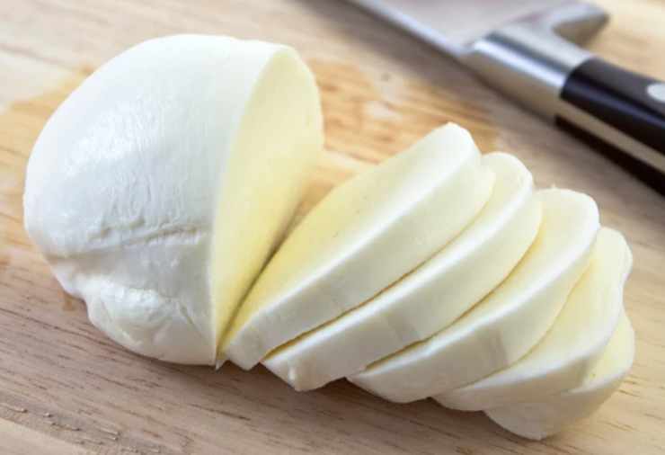 Aggiustiamo quindi il sale. Tagliamo la mozzarella ben sgocciolata a cubetti molto piccoli e sminuzziamo a mano le foglie di basilico fresco dopo averle late con cura;