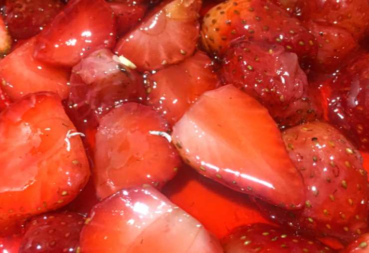Sgoccioliamo le fragole in una ciotola per prelevare il sugo (io uso uno scolapasta). Riversiamo i pezzi di fragole nella crema di mascarpone e panna e mescoliamo con una spatola tenendone da parte qualcuna per la decorazione;