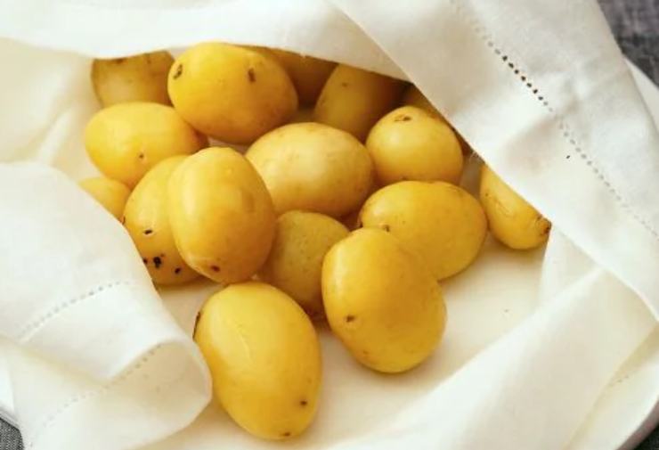 Lavate con cura le patate novelle sotto l’acqua corrente, strofinando la superficie con una spazzolina da cucina per eliminare ogni residuo di terra; lasciate la buccia intatta. Trasferitele in una pentola con abbondante acqua fredda leggermente salata, portate a bollore e cuocetele per circa 15-18 minuti. Fate la prova infilzandole con uno stecchino: deve penetrare facilmente senza sfaldare la patata. Scolatele e lasciatele raffreddare completamente.