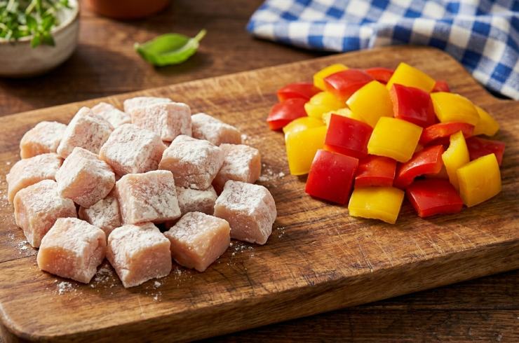 Prendete il petto di pollo, eliminate eventuali cartilagini e tagliatelo a cubotti della stessa dimensione.Infarinateli e scrollateli in un colino per eliminare l’eccesso. Lavate i peperoni, privateli dei filamenti e dei semi, quindi tagliateli a quadrotti della stessa misura del pollo. Affettate la cipolla rossa a spicchi non troppo sottili. Prendete ora un’ampia padella antiaderente e scaldate tre cucchiai di olio extravergine d’oliva.