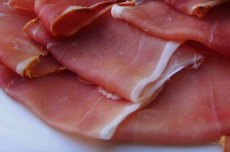 Posizionate al centro di ogni fettina due punte di asparagi sbollentati, lasciandole sporgere leggermente dai bordi superiori della carne. Arrotolate la fettina di pollo su se stessa partendo dalla base, racchiudendo l’asparago e il formaggio. Avvolgete ogni involtino così ottenuto con una fetta di prosciutto crudo, premendo leggermente con le mani: il prosciutto aderirà perfettamente alla carne bloccando l’involtino senza il bisogno di utilizzare stuzzicadenti o spago da cucina.