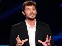 Stefano De Martino, conduttore di Affari Tuoi, parla con enfasi durante una trasmissione televisiva.