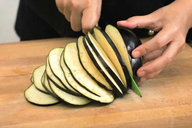 Lavate le melanzane e tagliale a fette regolari nel senso della lunghezza, poi scaldate una piastra di ghisa. Grigliate le fette di melanzana circa 2 minuti per lato, finché mostrano le classiche striature. Mano a mano che sono pronte, racchiudetele tra due piatti per farle ammorbidire con il vapore. In una ciotola, sbriciolate la feta greca con una forchetta. In un tagliere riducete i pomodorini a piccoli dadini (dopo averli privati dei semi in eccesso).