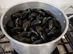 Pentola in acciaio colma di cozze fresche pulite pronte per la preparazione dell'autentica impepata di cozze napoletana.