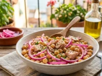 Insalata fredda di ceci, tonno e cipolla rossa di Tropea in una ciotola di ceramica su tavolo in legno