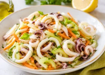 Insalata di calamari teneri con sedano croccante, carote julienne, prezzemolo fresco e citronette al limone servita in una ciotola bianca.