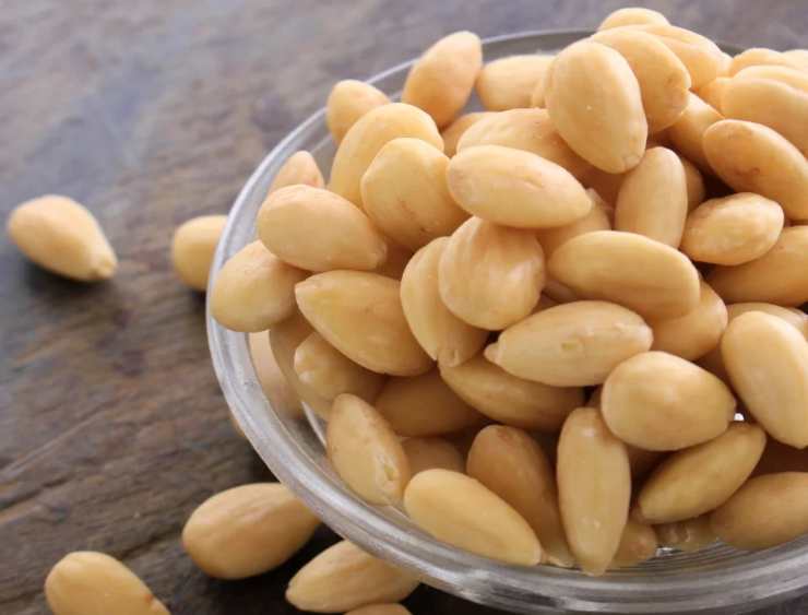 Mettete le mandorle pelate in un piccolo mixer e tritatele grossolanamente. Unite i fiori di zucca spezzettati con le mani, 4 filetti di alici sott’olio (tenendo gli altri due da parte per la finitura), il parmigiano reggiano grattugiato e, se gradito, un pezzettino di aglio privato dell’anima. Iniziate a frullare ad impulsi versando l’olio extravergine d’oliva a filo, fino ad ottenere una crema densa e omogenea. Se il pesto dovesse risultare troppo compatto, aggiungete un paio di cucchiai di acqua di cottura della pasta direttamente nel boccale del mixer.