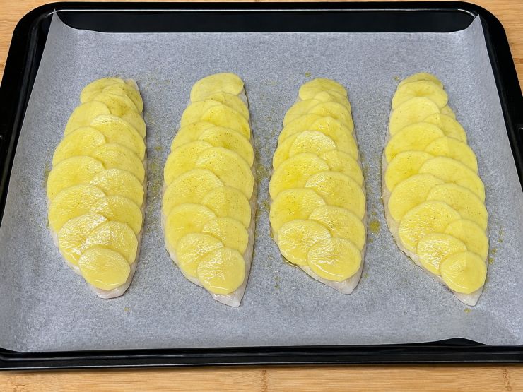 Disponete le rondelle di patate sopra ogni filetto, sovrapponendole leggermente come se fossero le squame di un pesce, coprendo interamente la polpa. Spennellate generosamente la superficie delle patate con l’olio extra vergine d’oliva rimasto e regolate di sale. Versate sul fondo della teglia il vino bianco secco, facendo attenzione a non bagnare la superficie delle patate. Cuocete in forno statico preriscaldato a 200 gradi per 15 minuti. Successivamente, attivate la funzione grill a 220 gradi per altri 5 minuti fino a quando la crosta risulterà dorata e croccante. Sfornate e servite subito ben caldo: buon appetito!