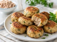 Polpette di tonno morbide e dorate servite su un piatto con prezzemolo fresco e spicchi di limone.